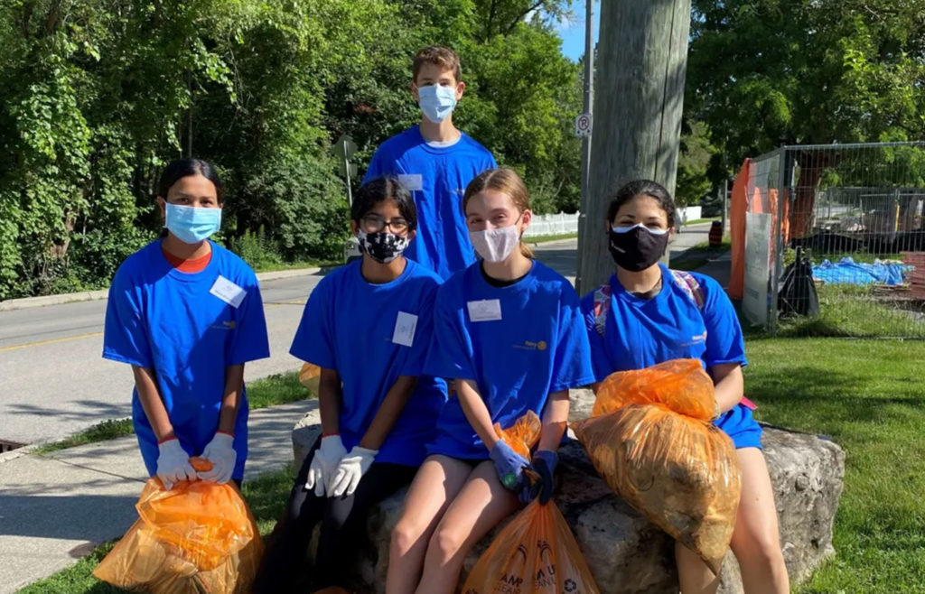 group of volunteer youth holding bags of trash they cleaned up