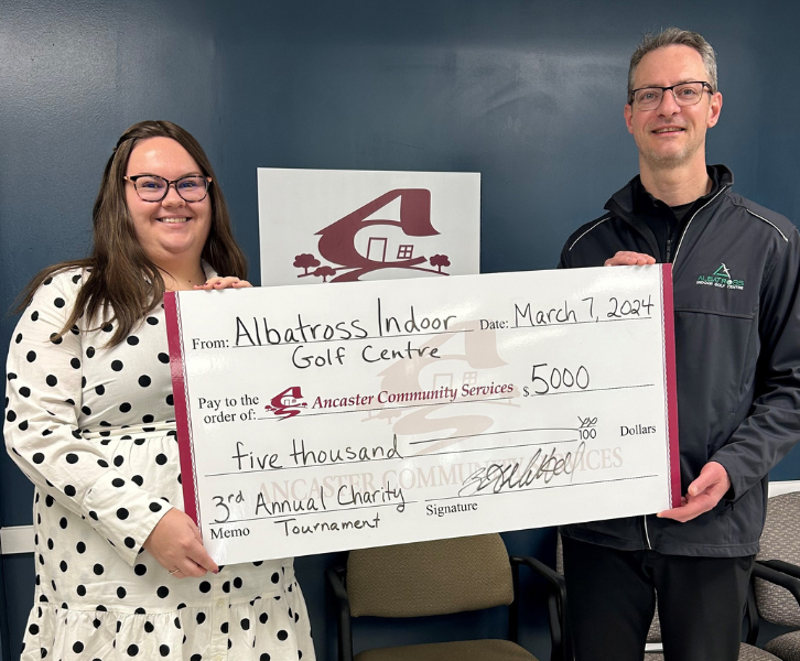 photo of two people holding a large donation cheque